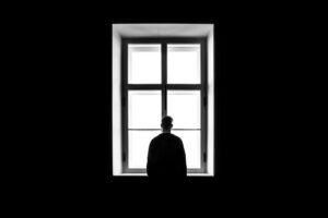 A man standing alone in front of a window